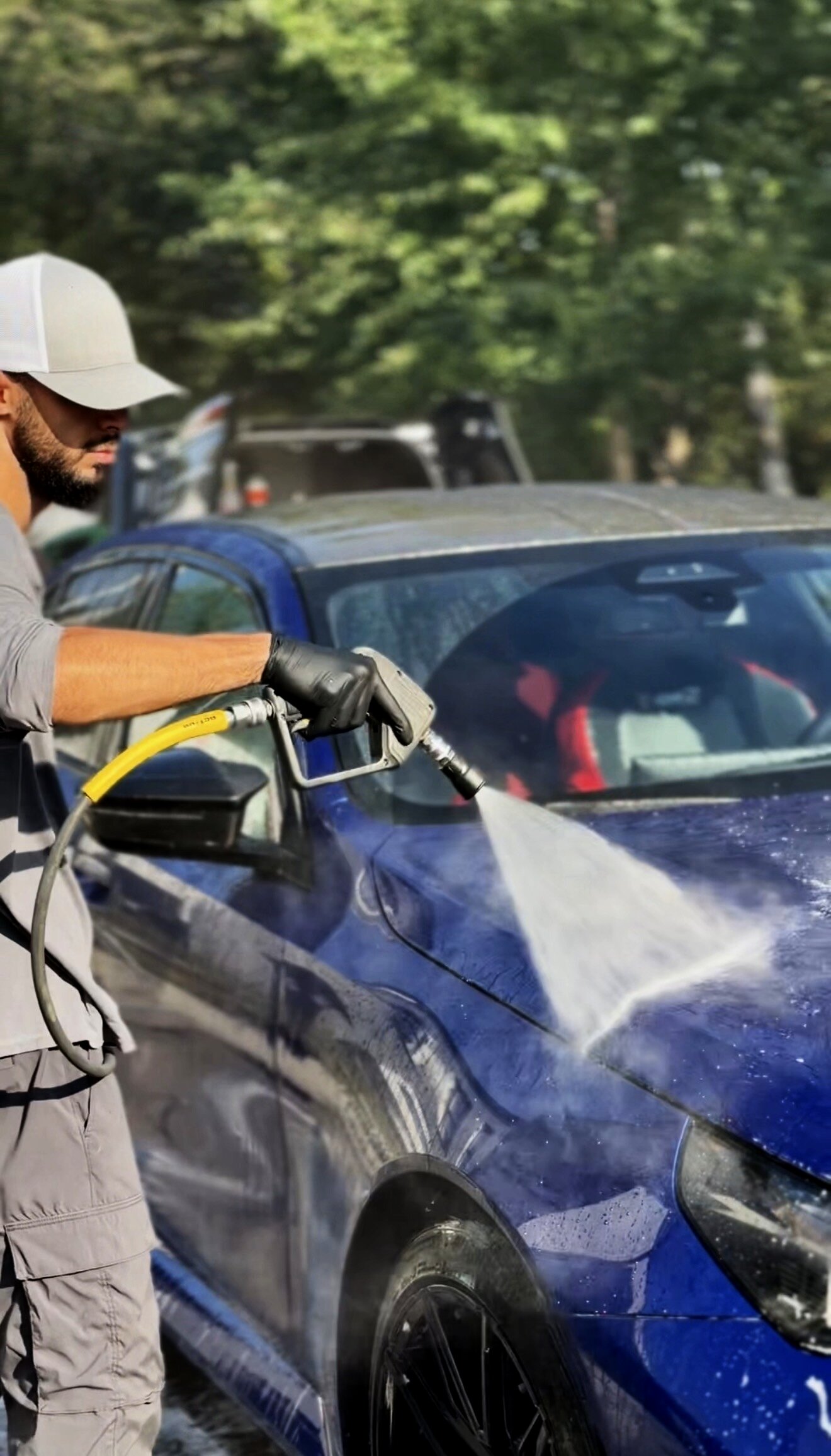 Detailer van Eye For Detailing spoelt een blauwe BMW af tijdens een handwas aan huis
