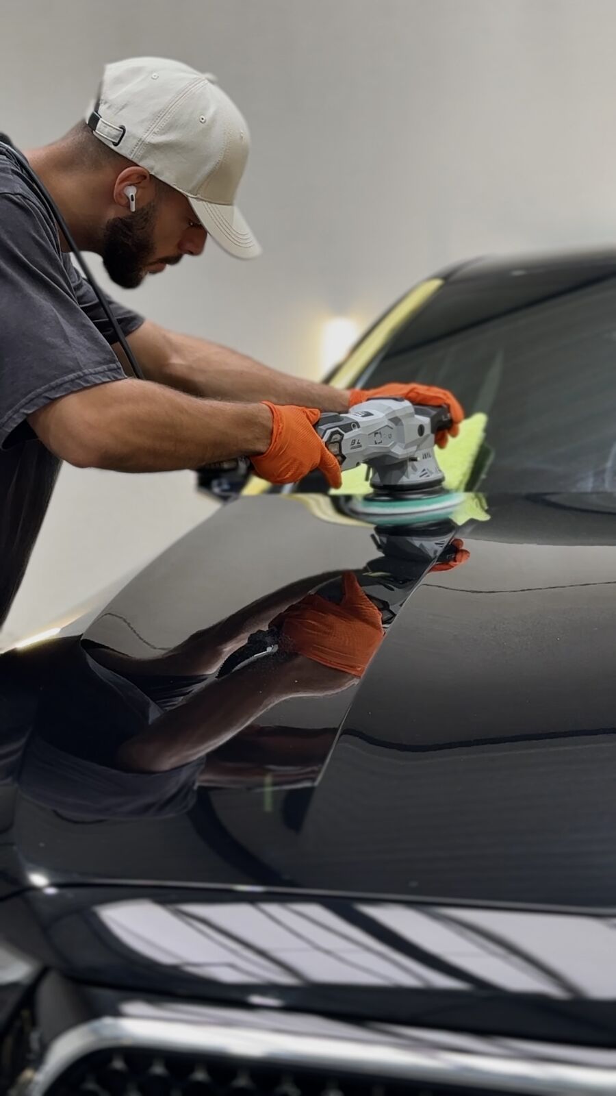 Trainer van Eye For Detailing polijst de motorkap van een zwarte wagen tot een spiegelende glans